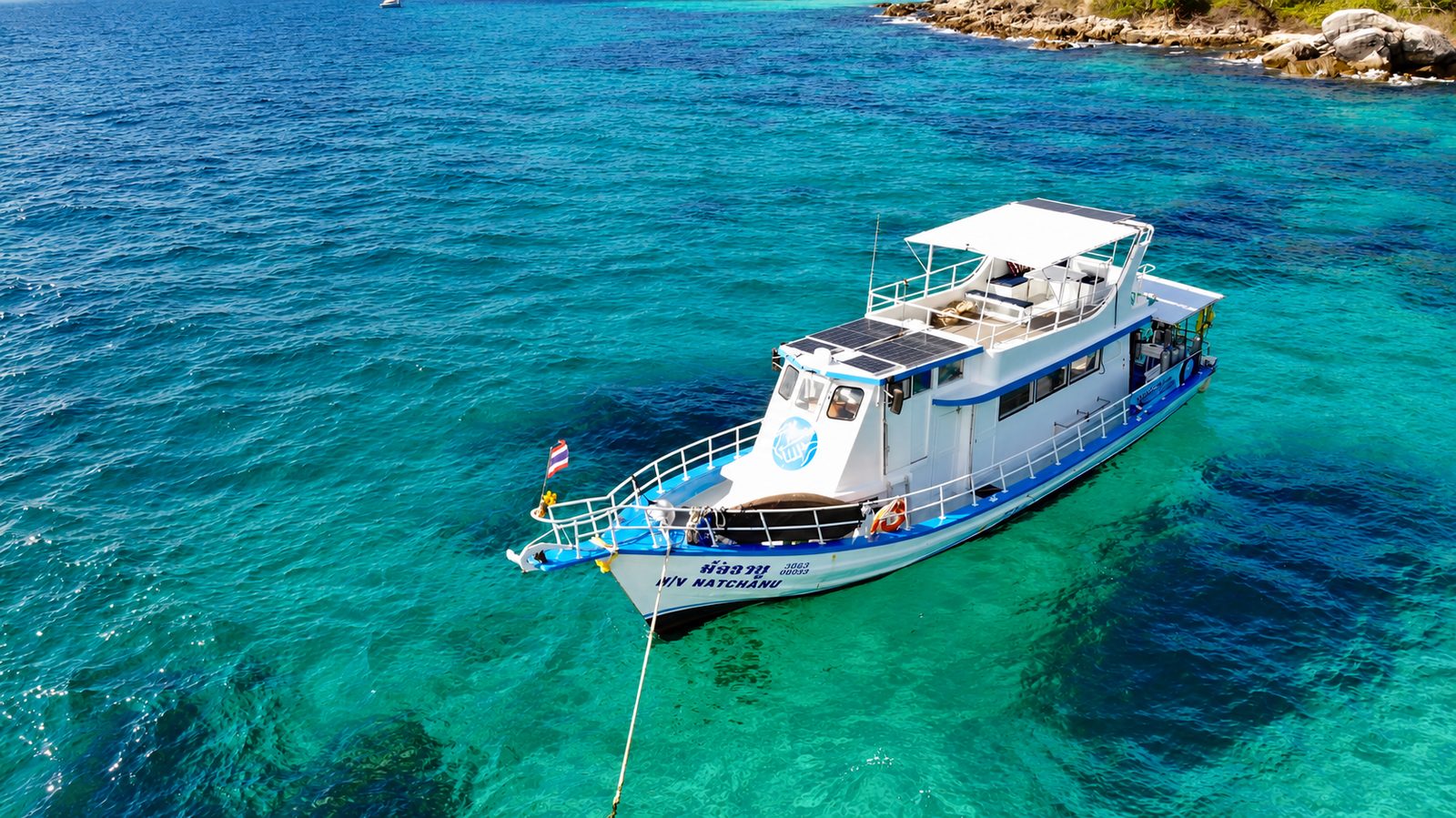 MV Matchanu from the air, at anchor in the turquoise water of Siam Bay