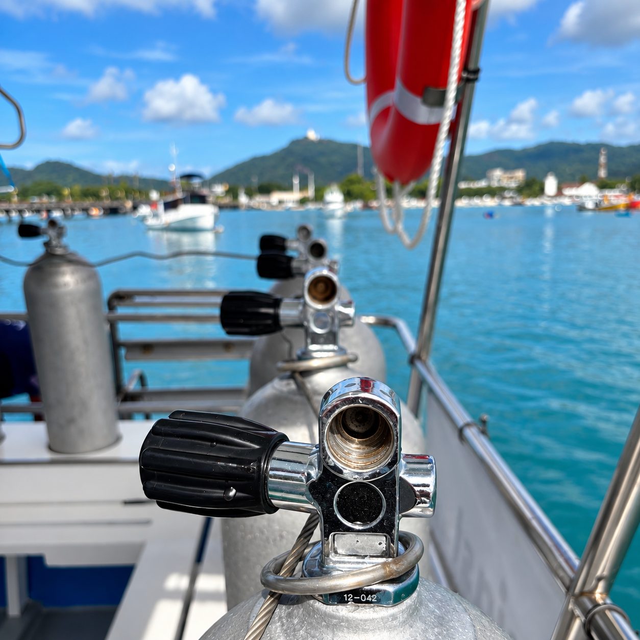 Tanks racked on the dive deck, a regulator first stage fitted, the harbour behind