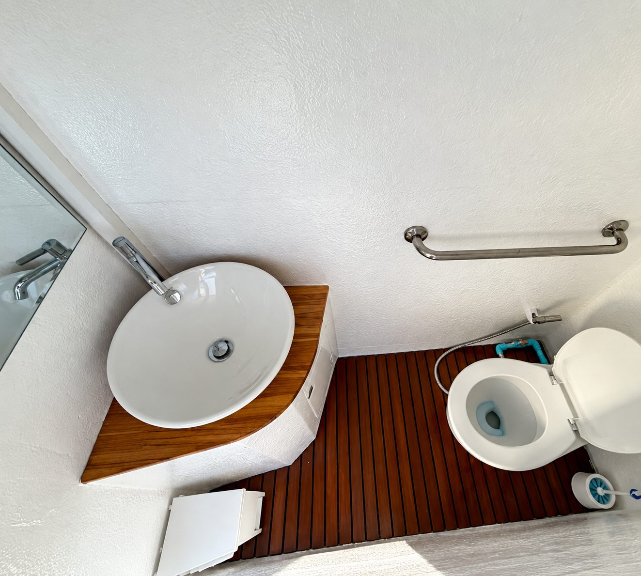 The head: a round basin on a wooden counter, a toilet and a teak floor