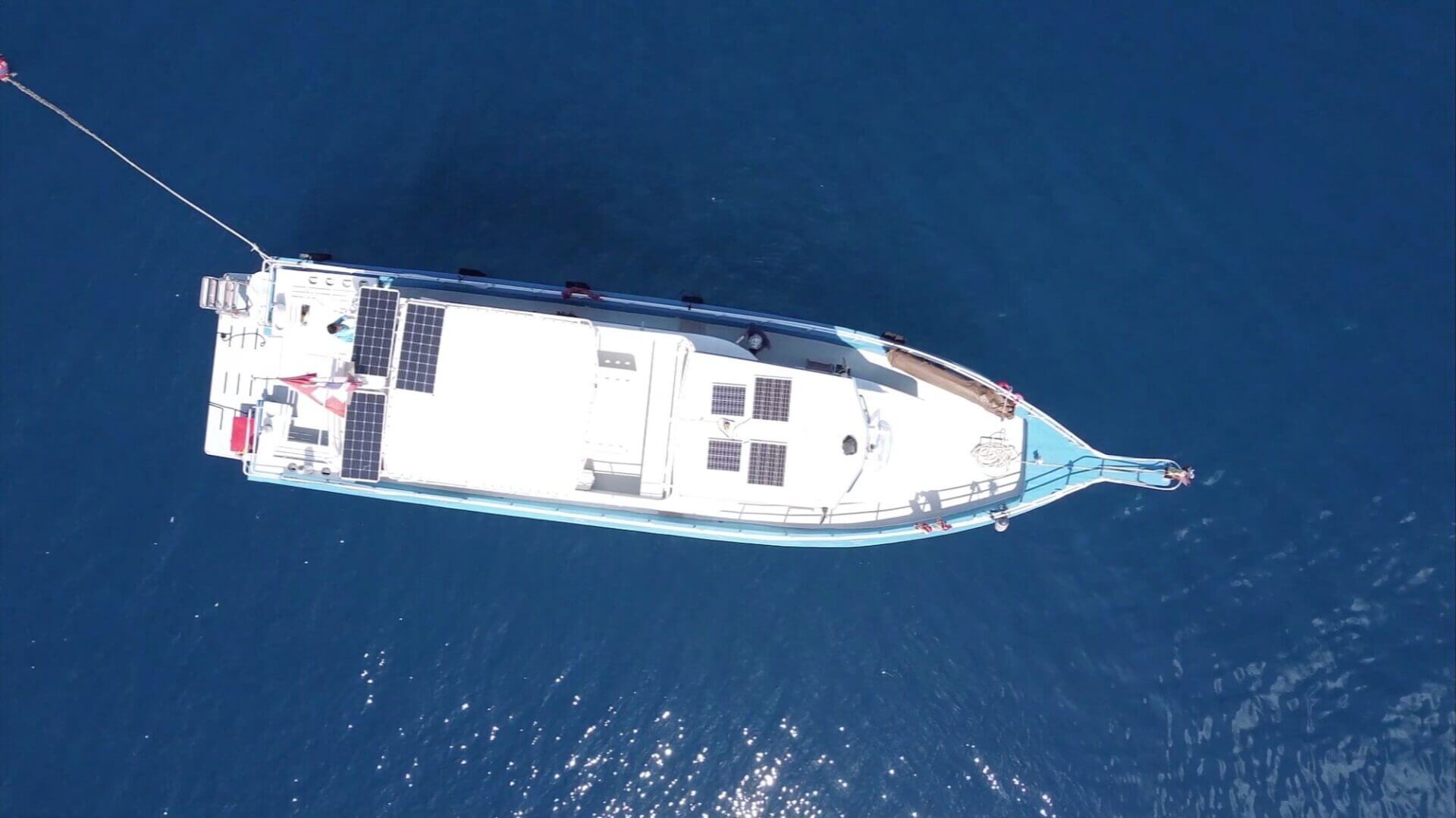 MV Matchanu seen from directly above, the solar panels covering its roof, in deep blue water