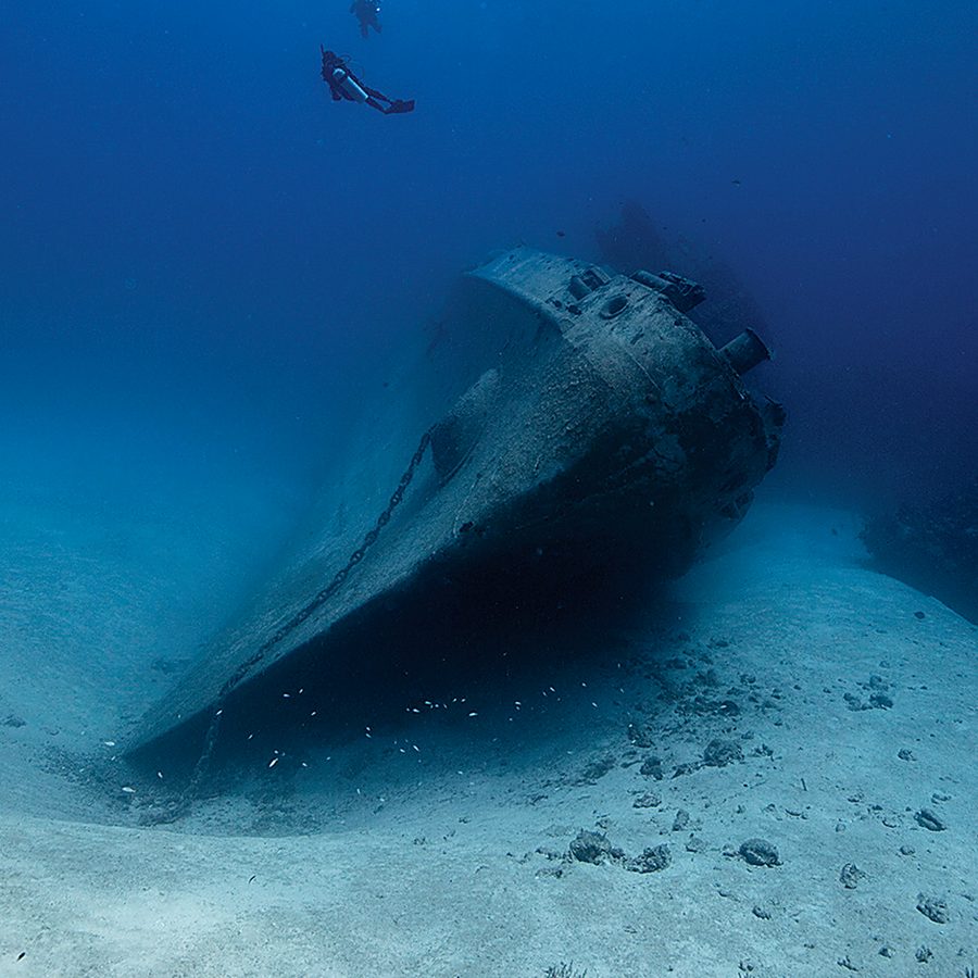 A diver over the hull of a wreck on the sea floor (PADI)