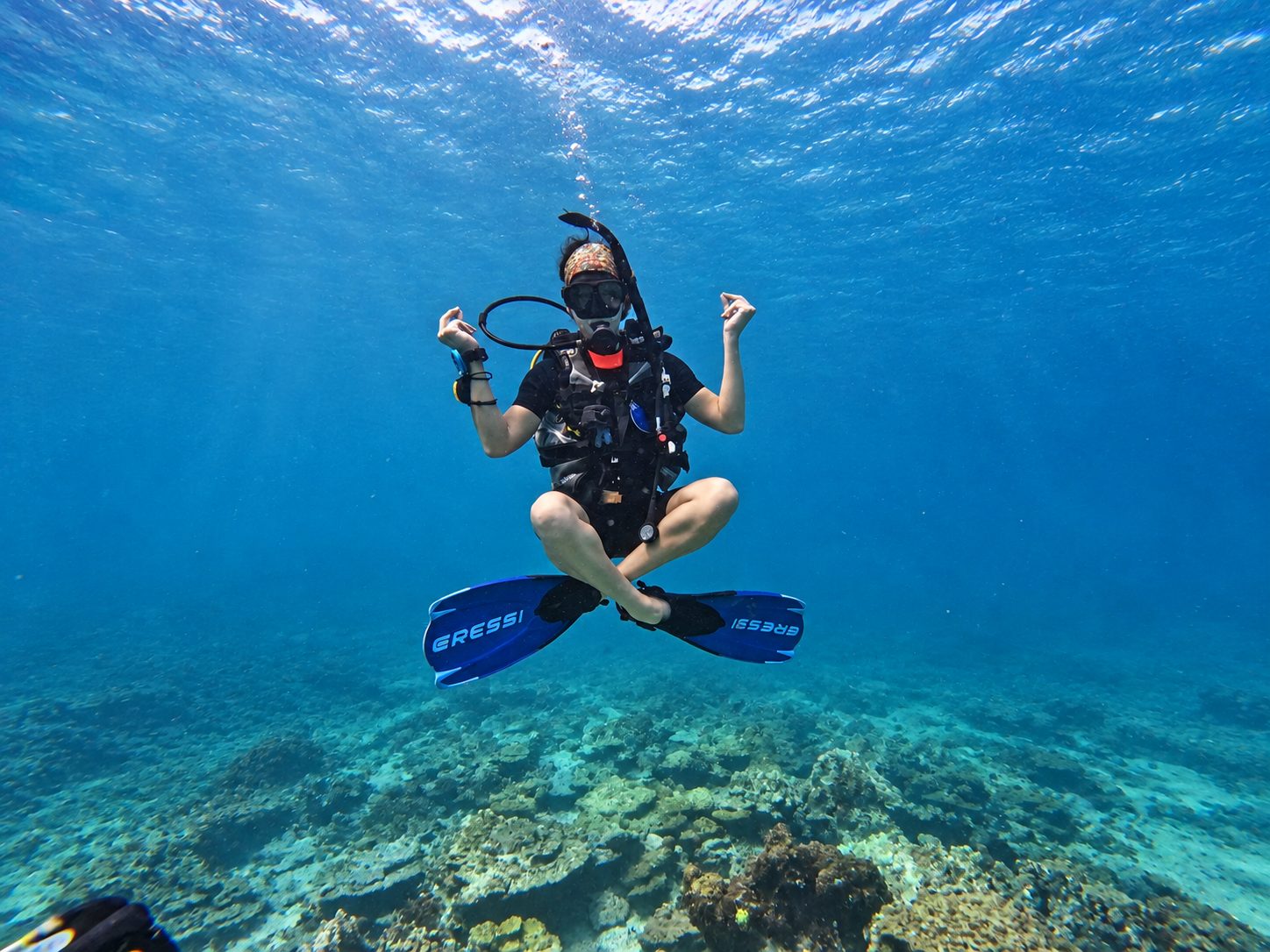 A diver hovering cross-legged above the reef — buoyancy practice