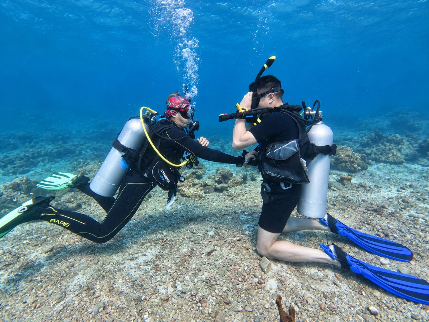 Two divers kneeling on the sand practising skills