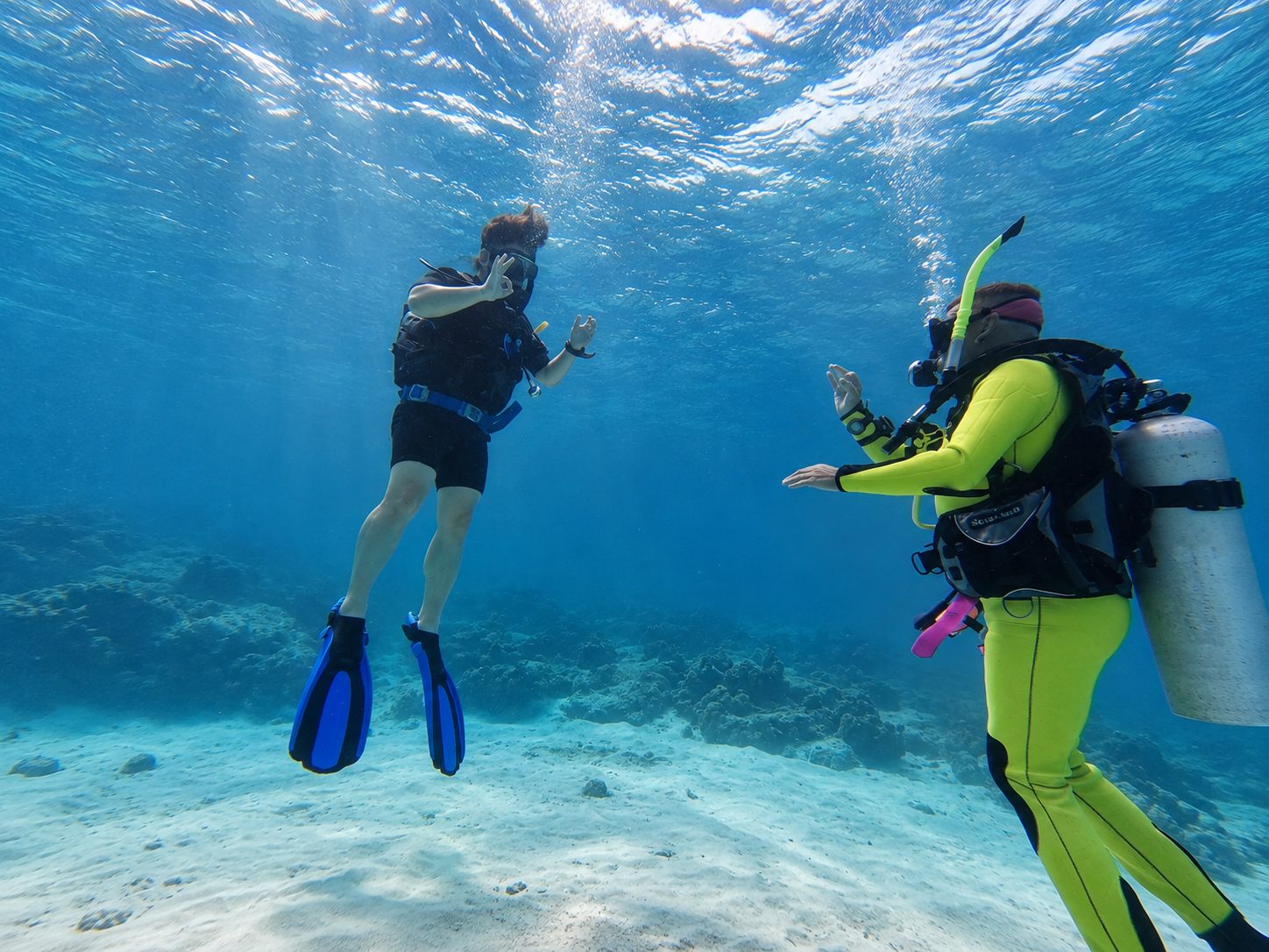 Two students hovering over the sand with their instructor