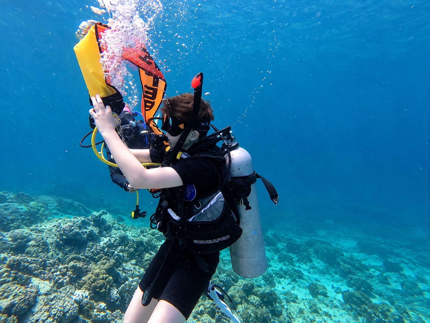 A diver deploying a surface marker buoy