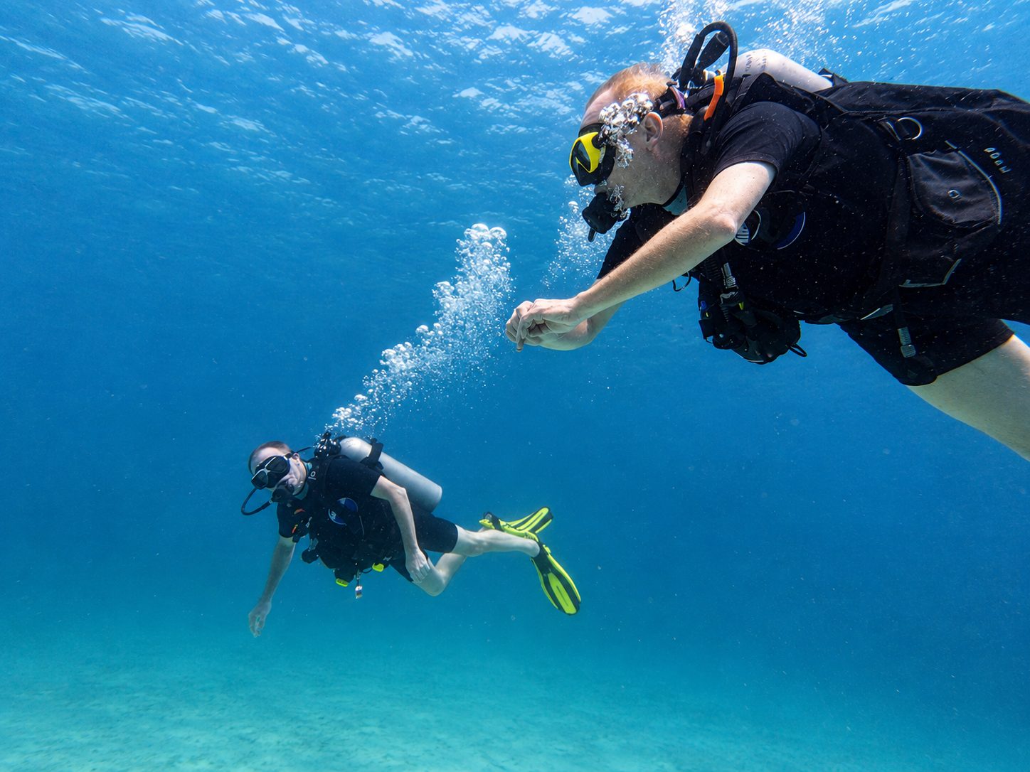Instructor and student descending together over the sand
