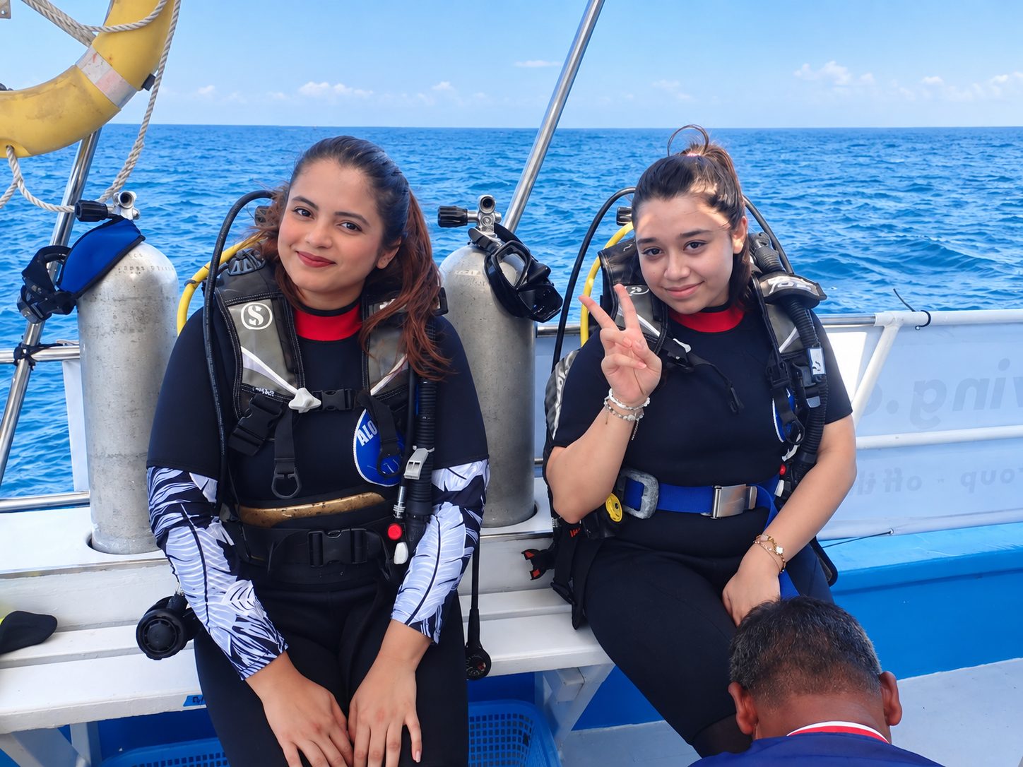Two guests in scuba gear on the boat bench before their first dive