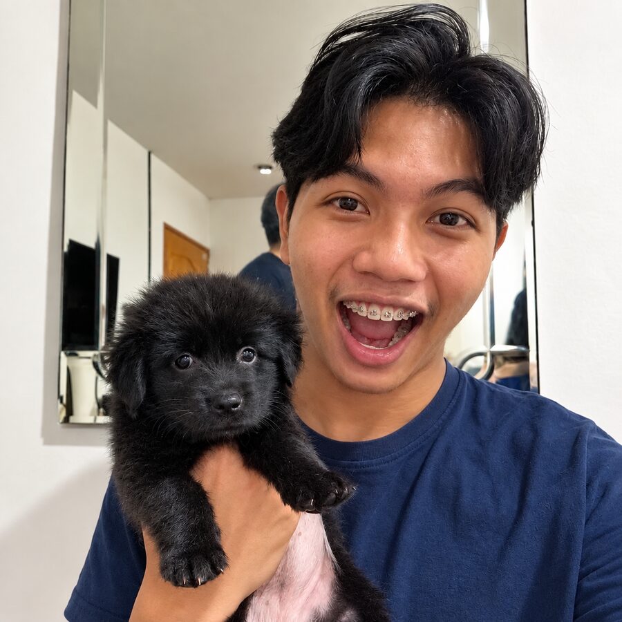 Bew laughing while holding a black puppy