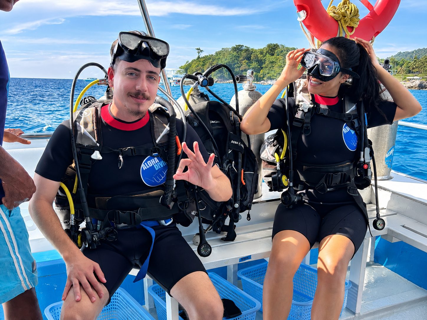 Two divers pulling on their masks on the dive-deck bench