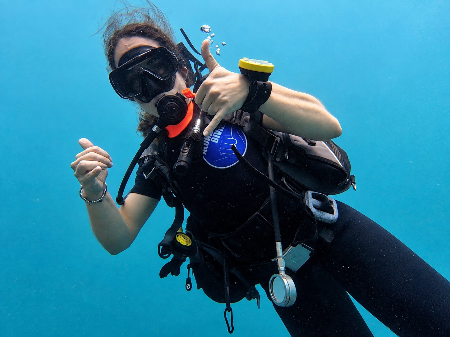 A diver giving a thumbs-up and a shaka underwater at Koh Doc Mai