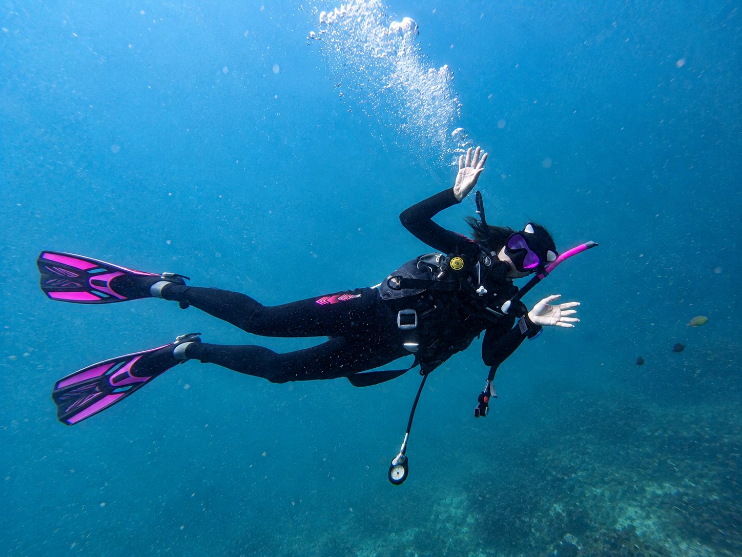 A diver with pink fins waving to the camera at Koh Doc Mai