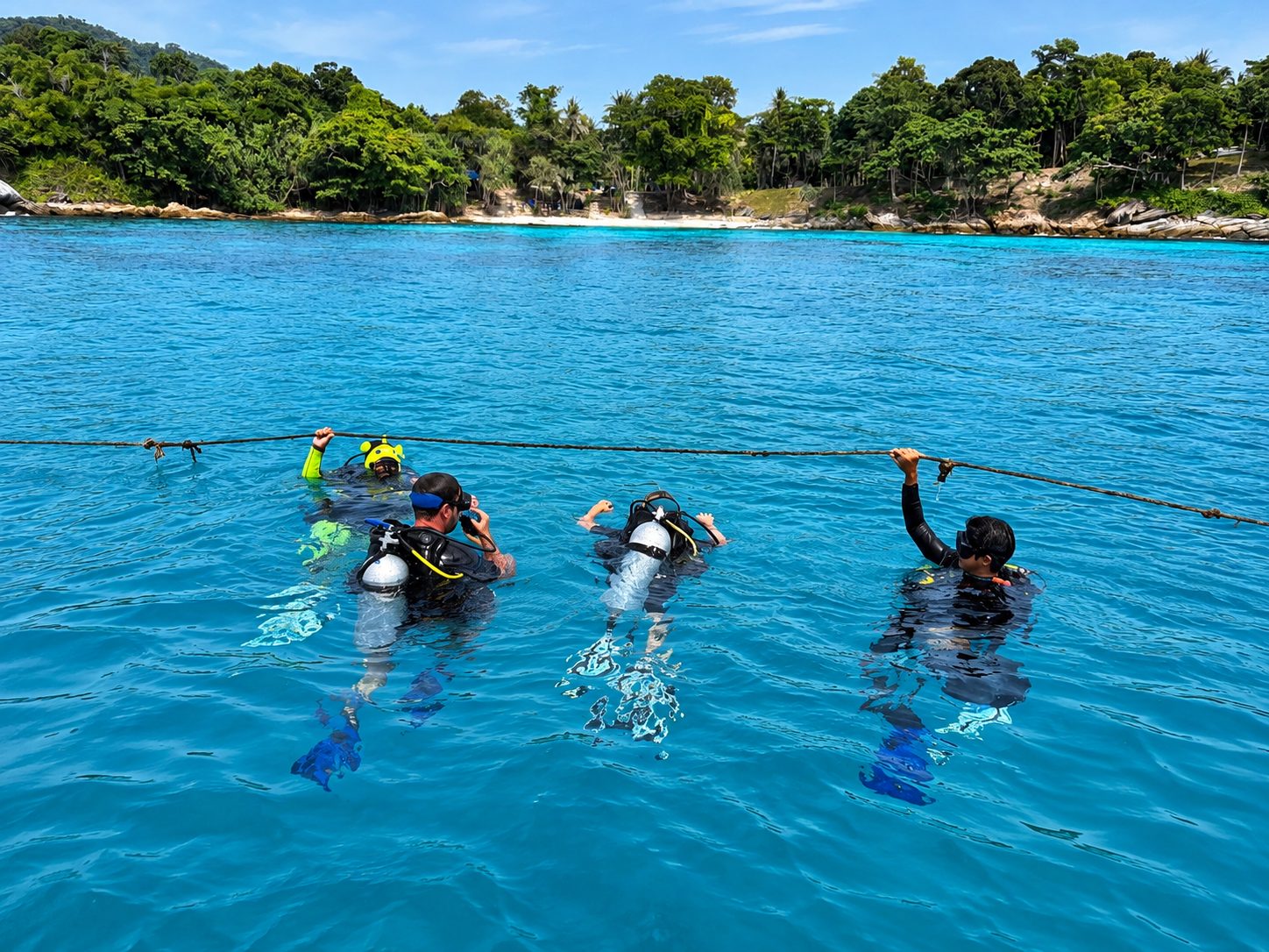 Three divers on the surface at the drop line beside the island