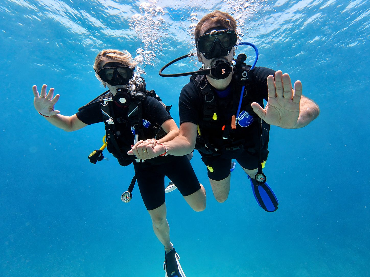 Two divers underwater waving to the camera