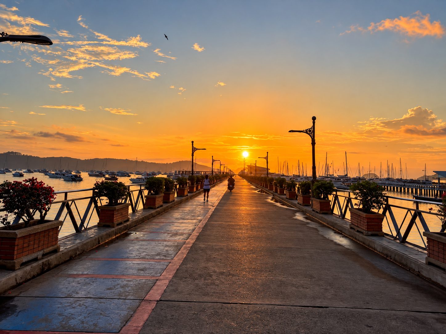 Chalong Pier at sunrise, the walkway empty and the sky orange