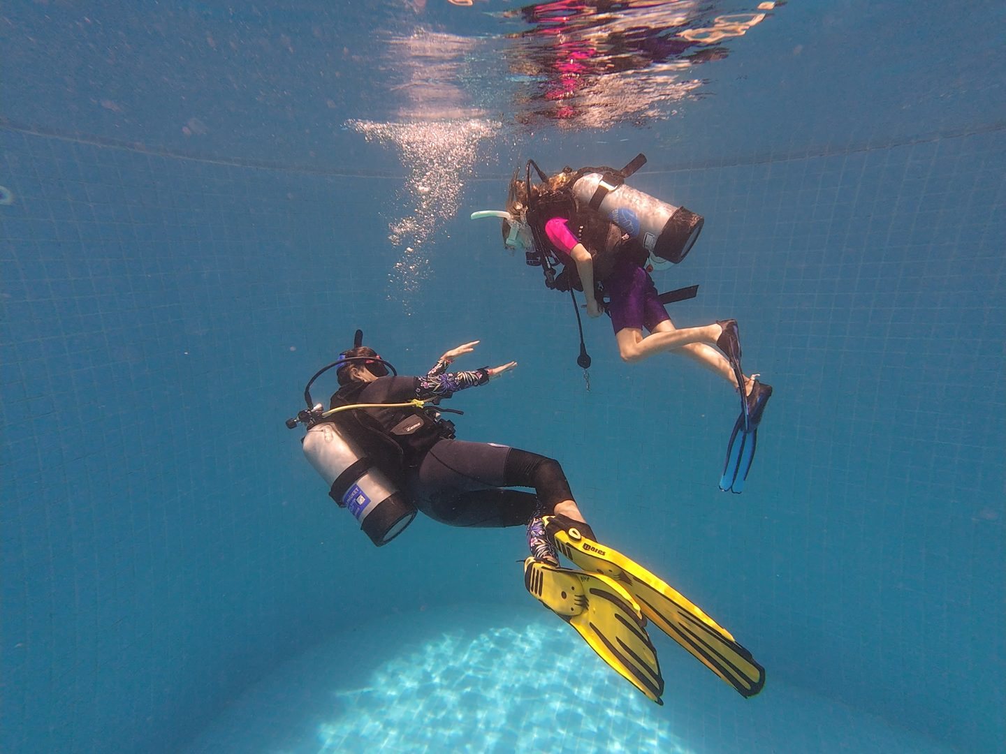 Two children in scuba gear on the floor of the training pool