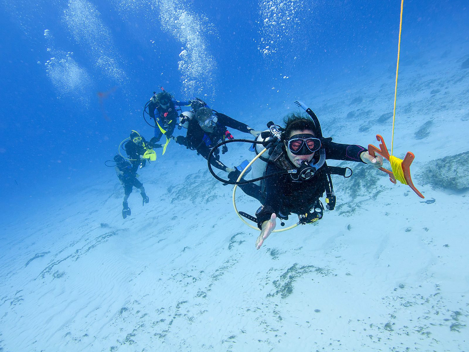 Divers on a drift dive, a reef hook line trailing (PADI)