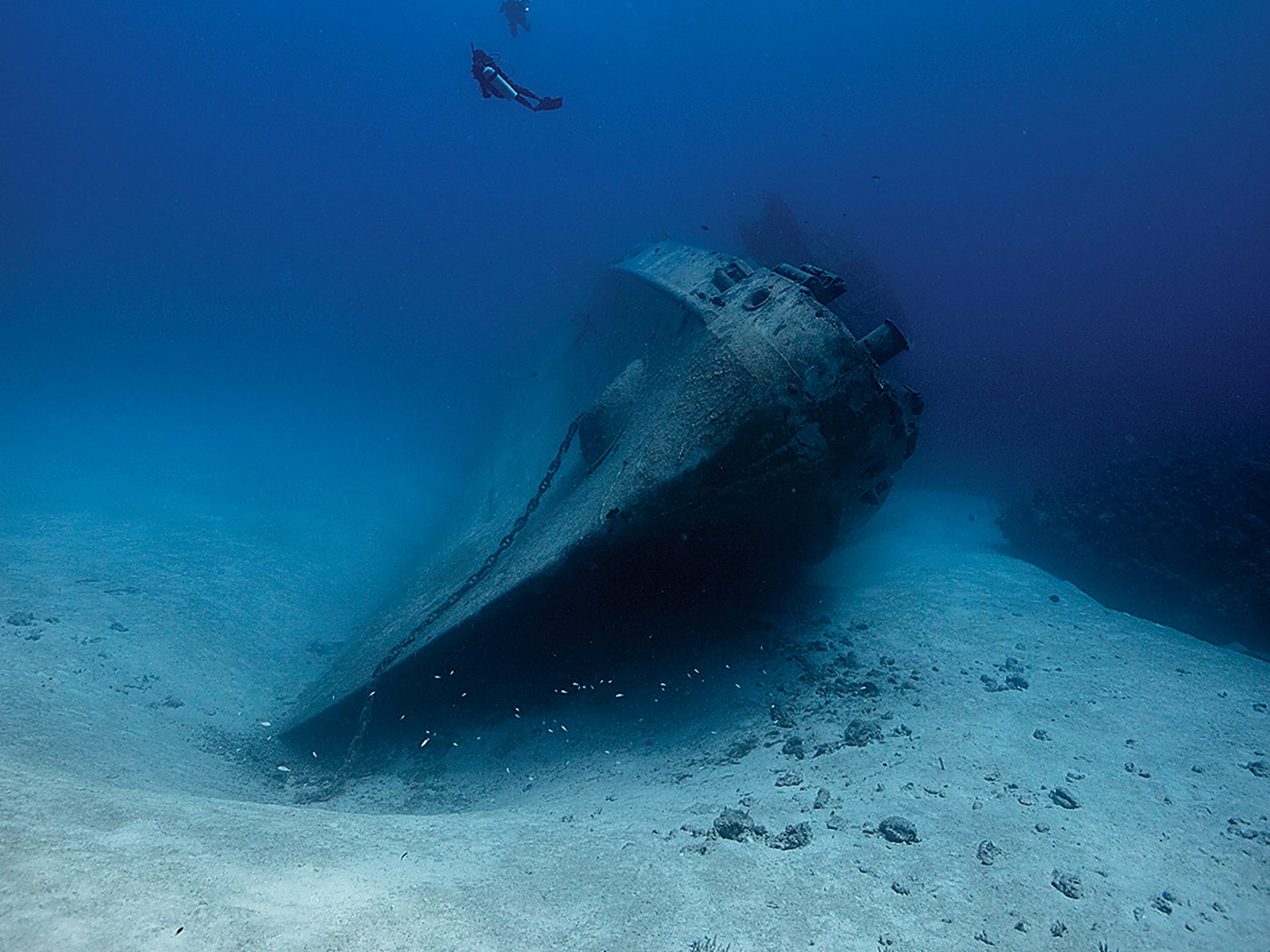 A diver over the hull of a wreck on the sea floor (PADI)