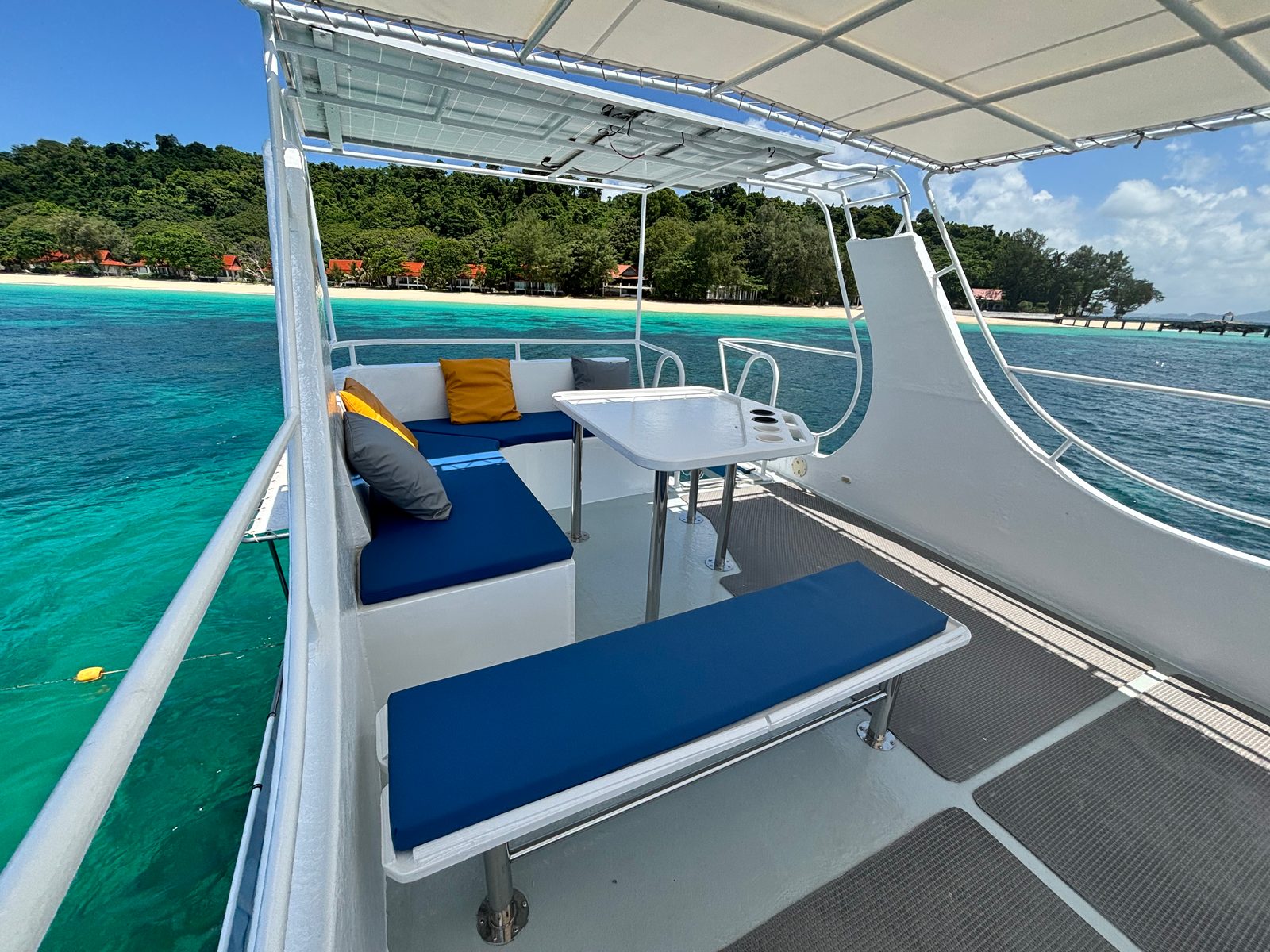 The sun deck’s blue benches and table, a palm-lined beach beyond