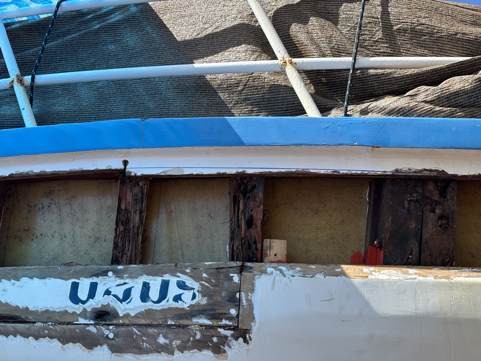 A section of the bulwark opened up to replace rotten timber, the old planking exposed beside the Thai lettering