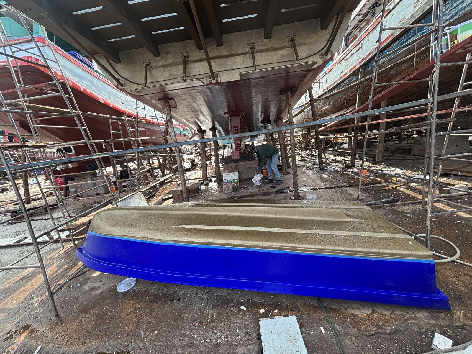 Her hull with new blue antifouling below the waterline, in the shed among the other boats