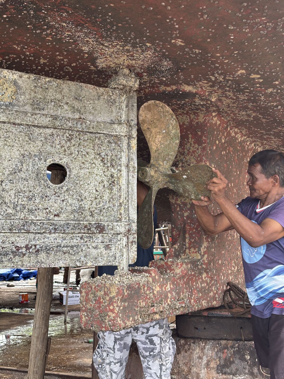 A worker scraping fouling from the rudder and propeller before the new paint goes on