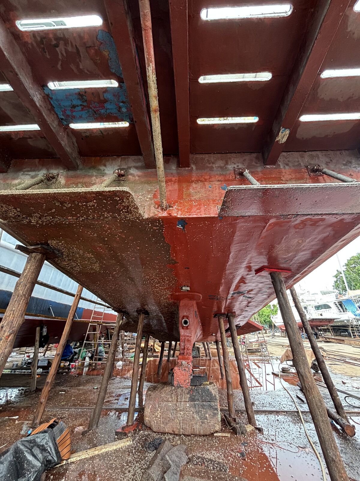 The hull in red primer below the waterline, propeller and shaft exposed on the blocks