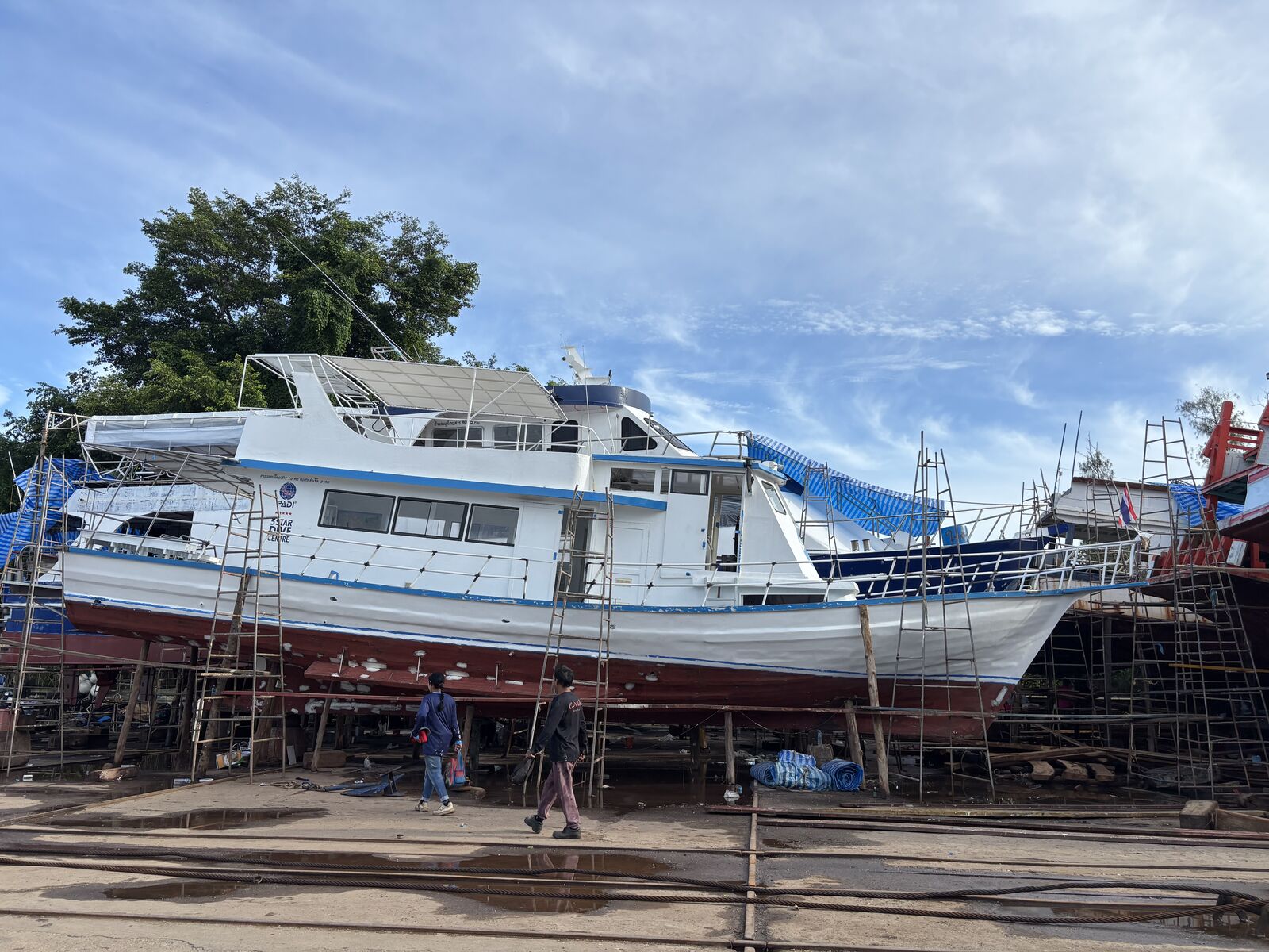 MV Matchanu on the slipway under a blue sky, other boats along the yard behind her
