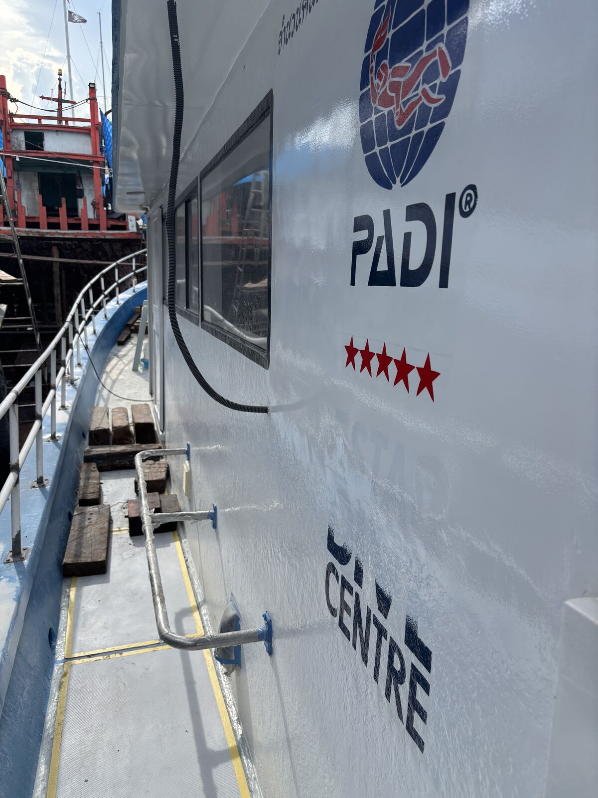 The PADI five-star centre lettering on the cabin side, the hull freshly repainted white