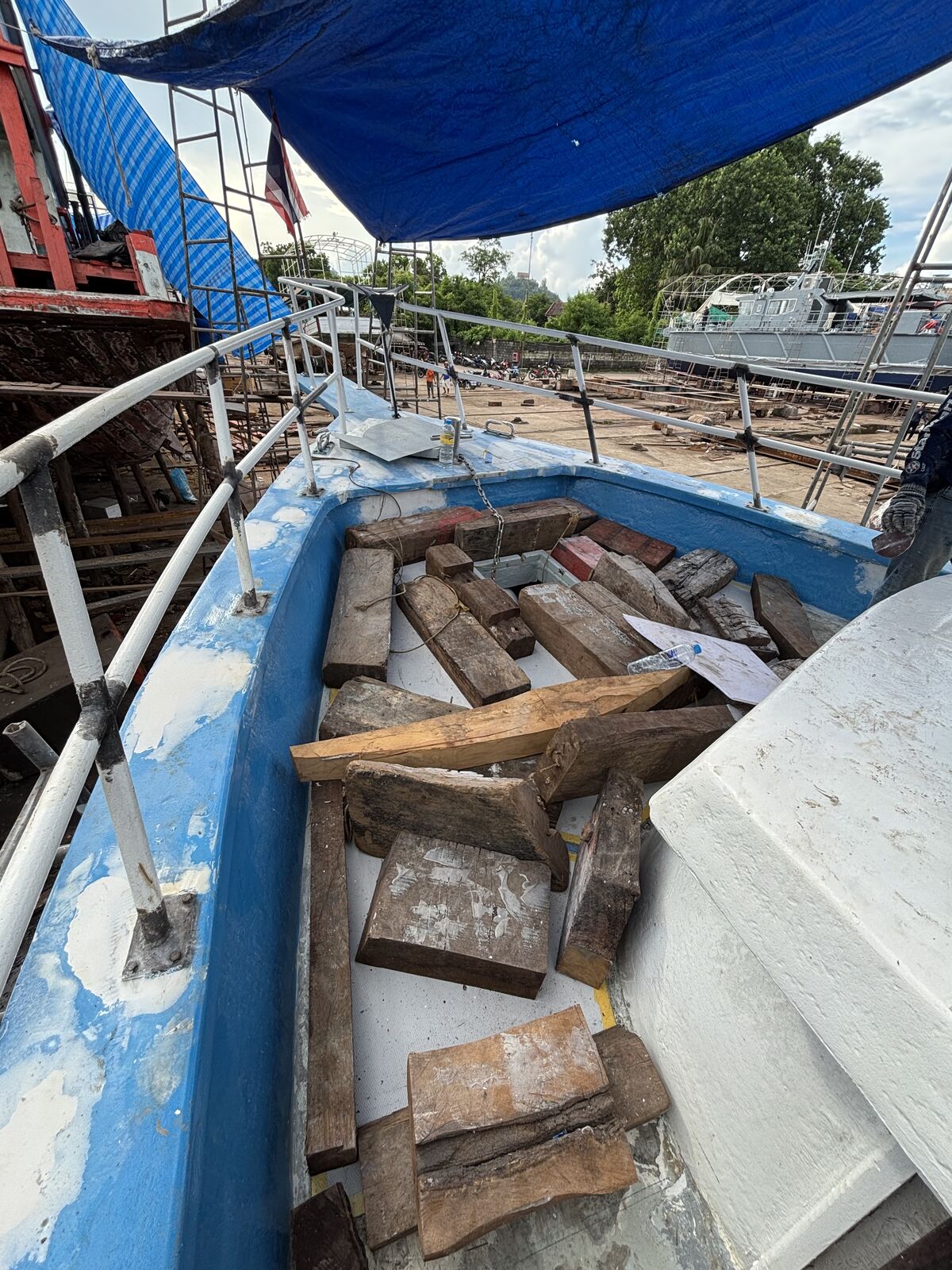 Timber offcuts stacked in the bow under a blue tarpaulin during the refit