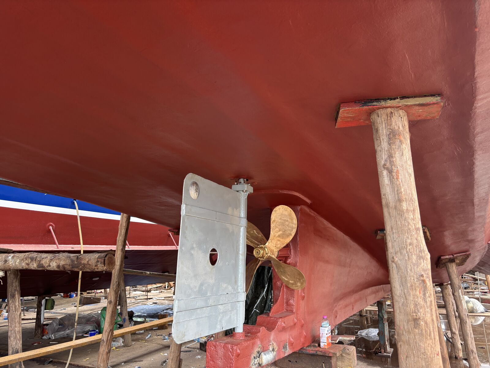 Fresh red antifouling on the hull, the rudder and bronze propeller repainted and propped on timber
