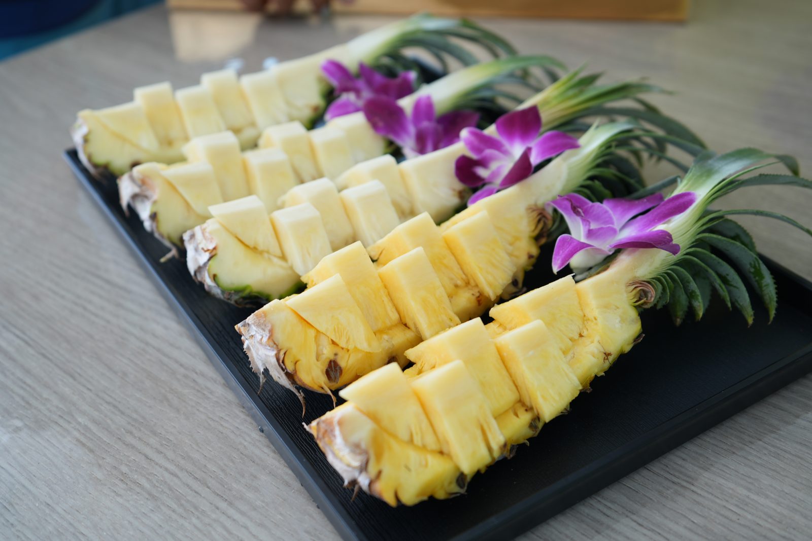 Sliced pineapple and orchids on a platter